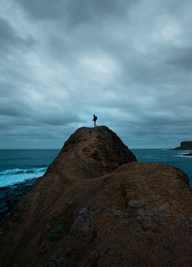 A traveler standing on a cliff overlooking a serene ocean at sunset, embodying freedom and adventure.