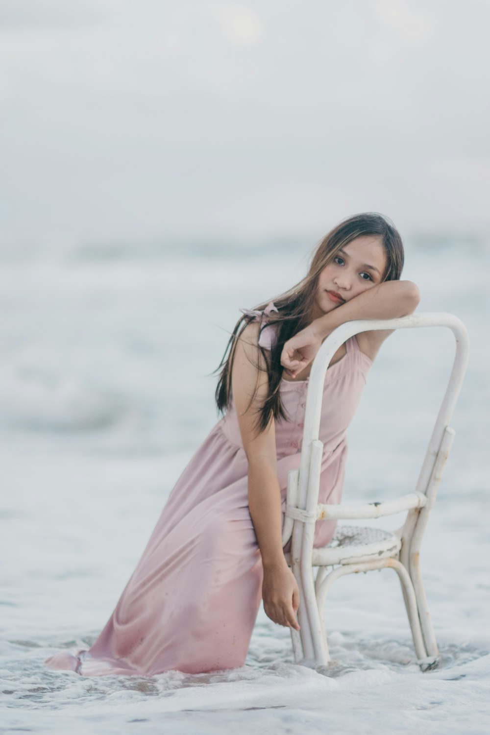 woman wearing pink dress sitting on white chair