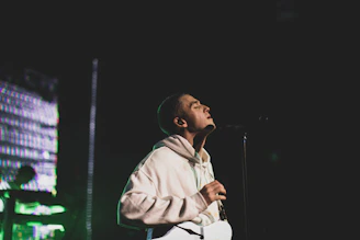 A close-up of Bossman Hogg passionately rapping into the microphone under colorful stage lights.