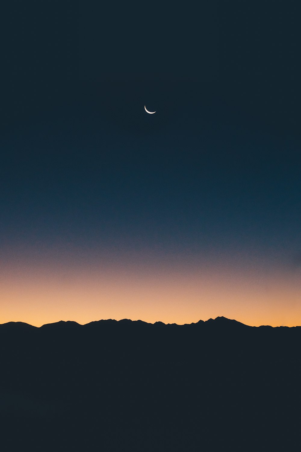 silhouette photography of land under a crescent moon during golden hour