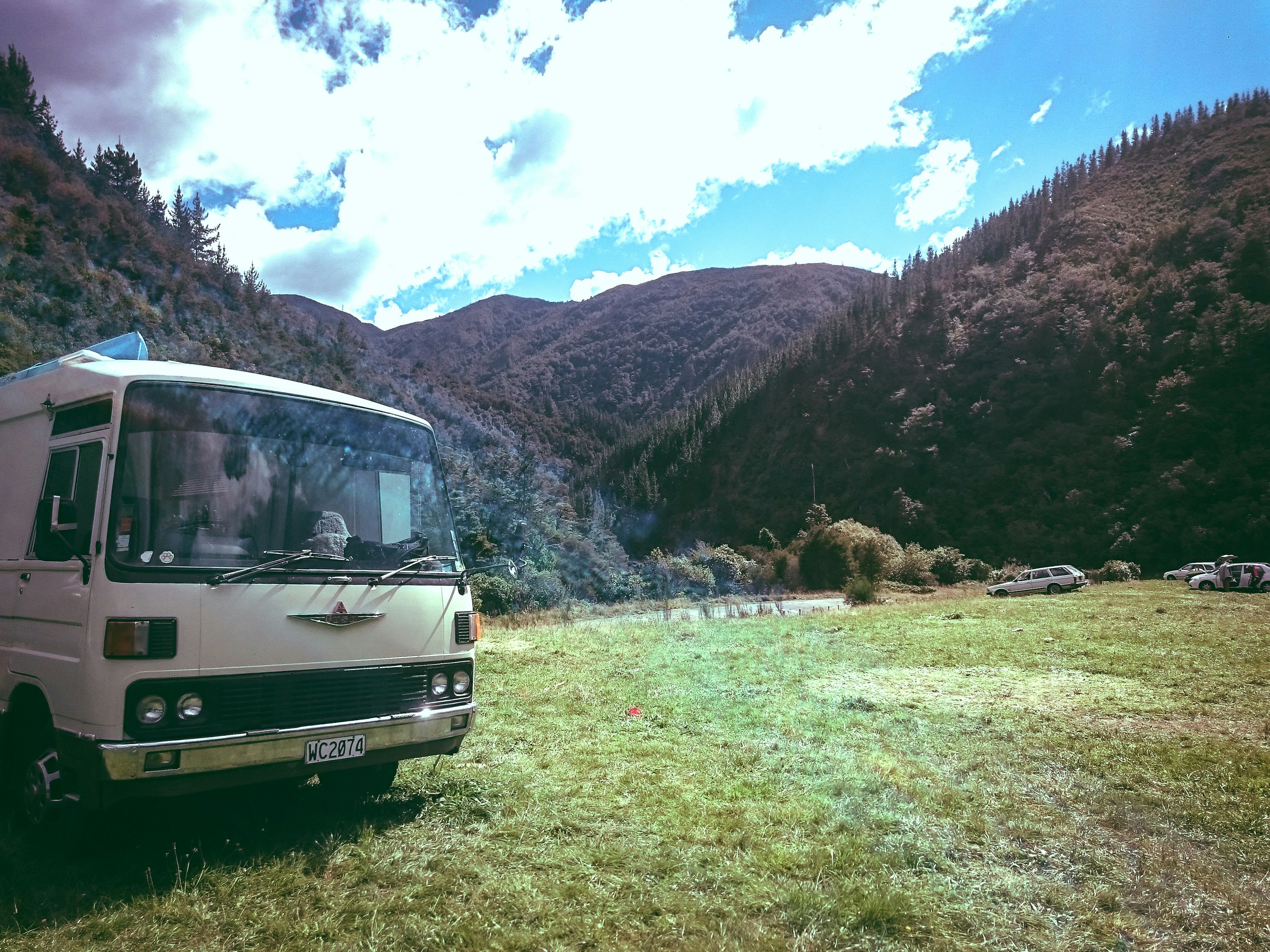 white van parked near mountains under cloudy sky