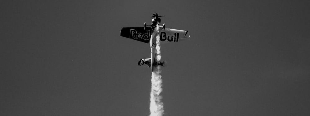 grayscale photo of biplane releasing smoke