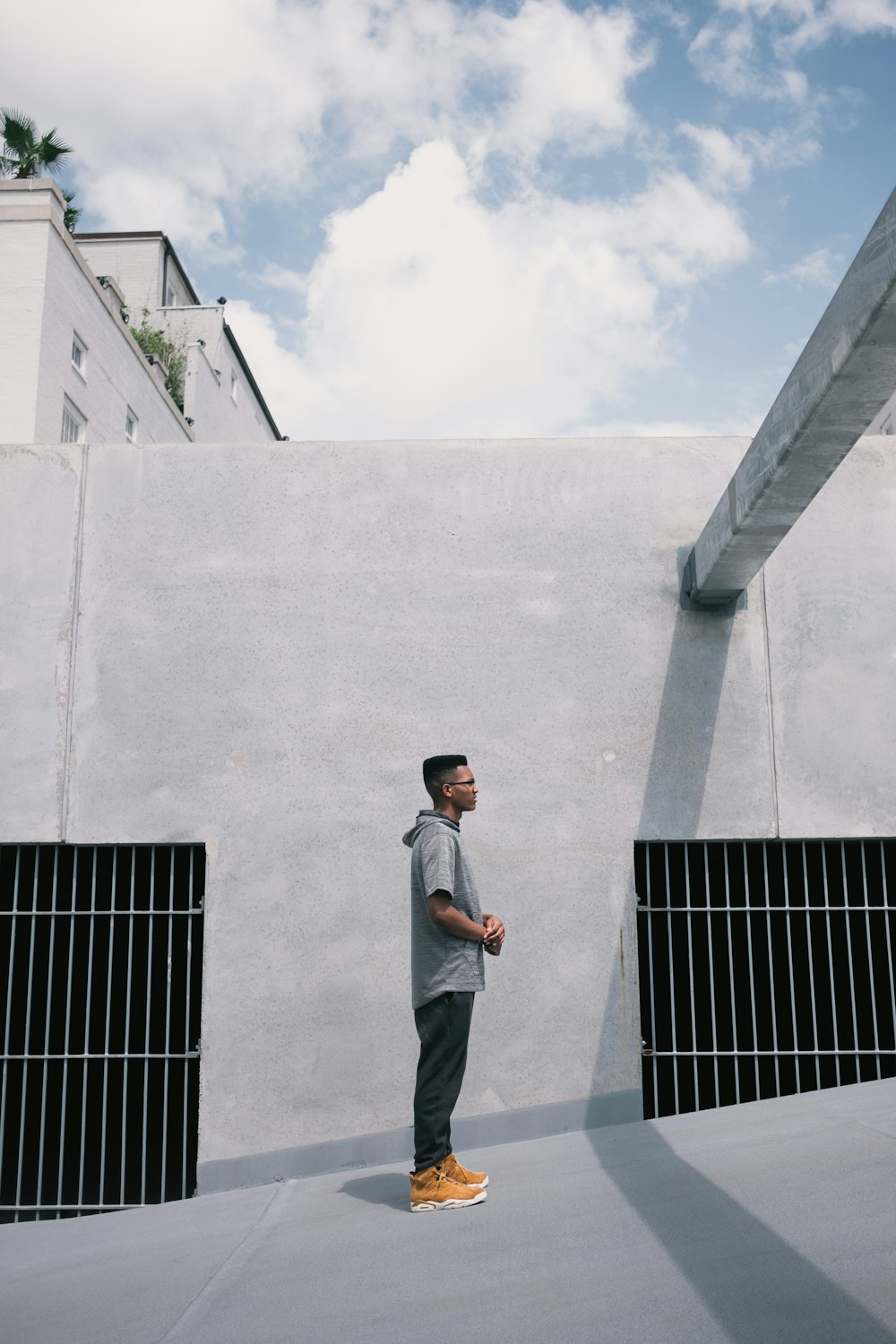 man wearing gray hooded shirt standing on gray wall