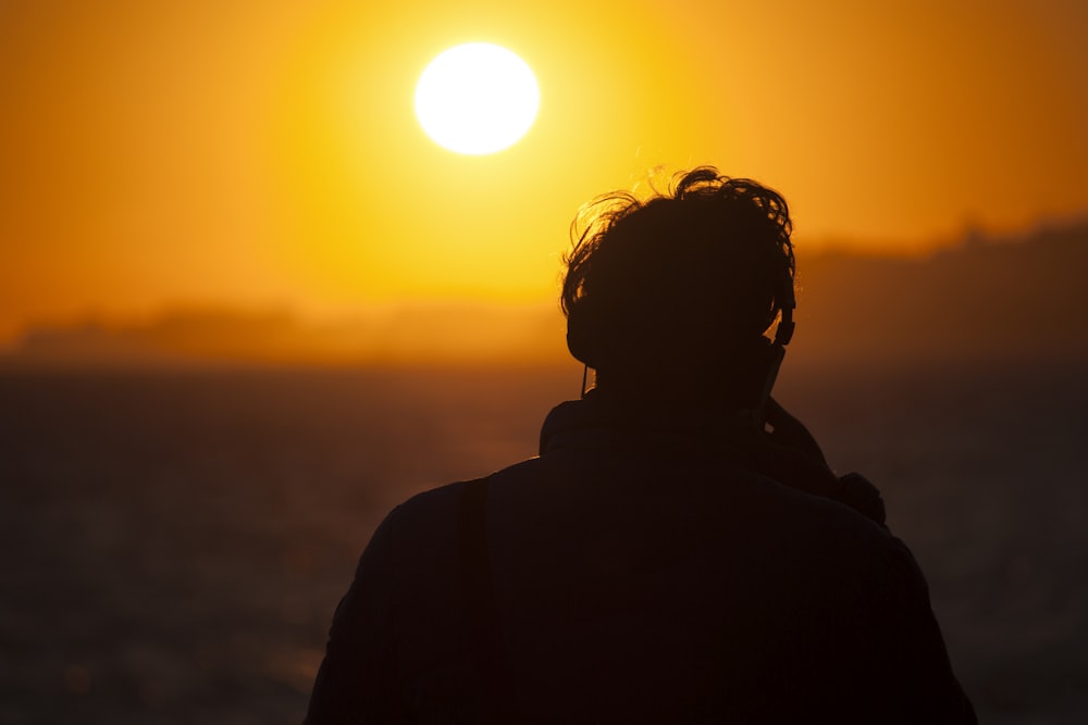 silhouette of man watching sunset