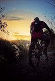 Mountain biker riding through a rugged desert trail at sunset in the American Southwest.