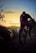 A happy cyclist riding a mountain bike on a forest trail during sunset.