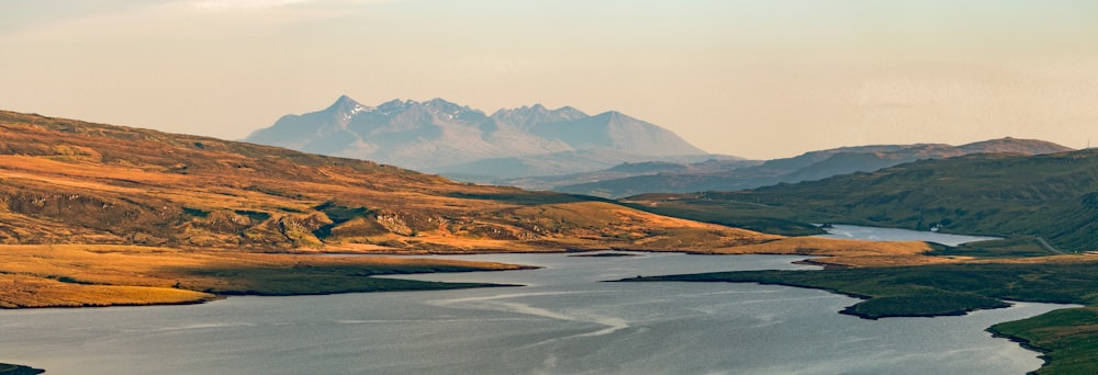 brown mountain near body of water under white clouds