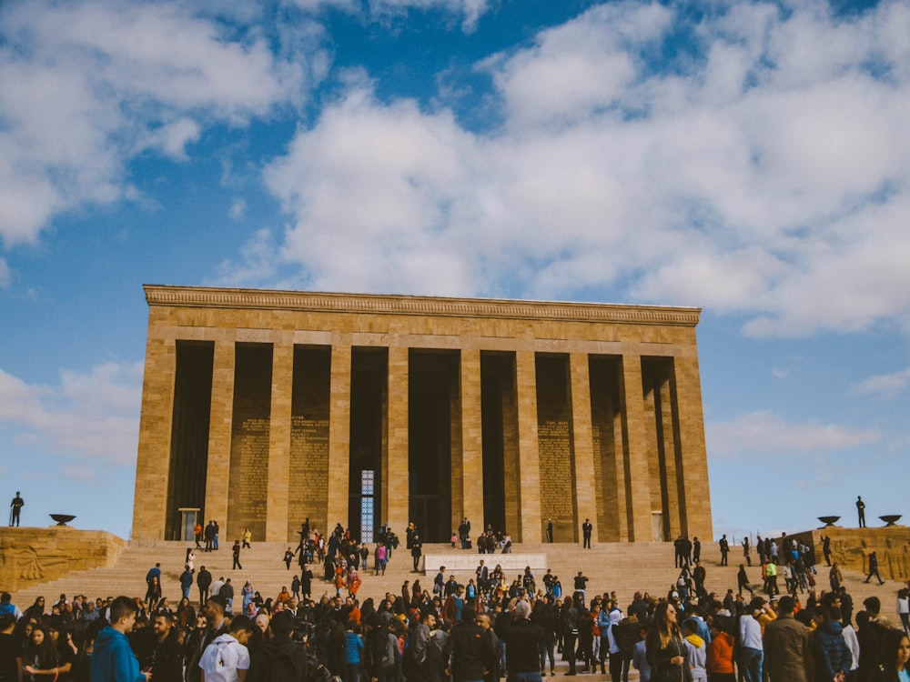 people gathering near brown building under white clouds