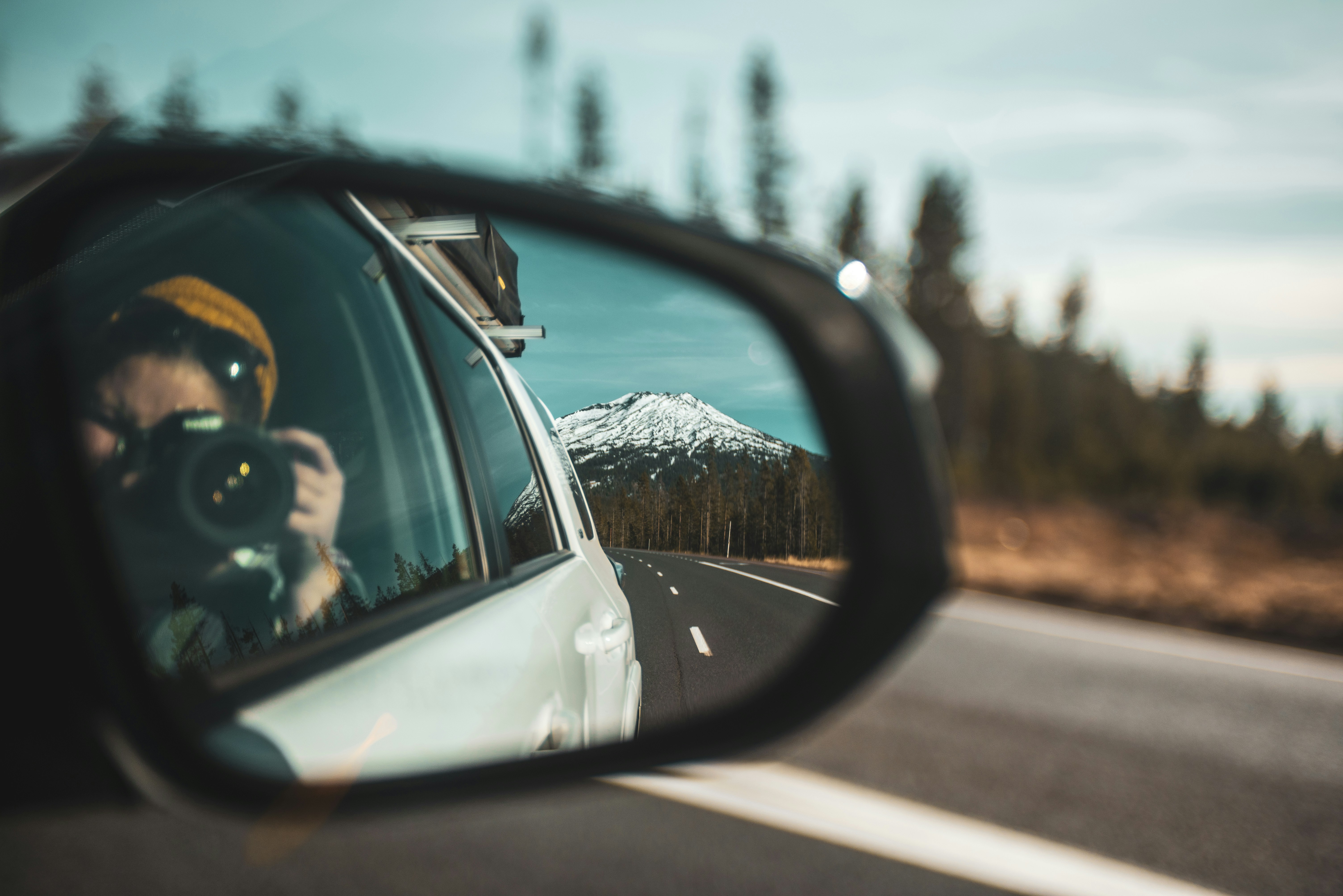 6 Road Trip Essentials Most People Forget (Until It’s Too Late) – close-up photography of woman taking photo of mountain through vehicle side mirror