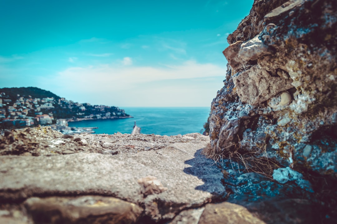 houses on cliff viewing blue sea under blue and white sky during daytime