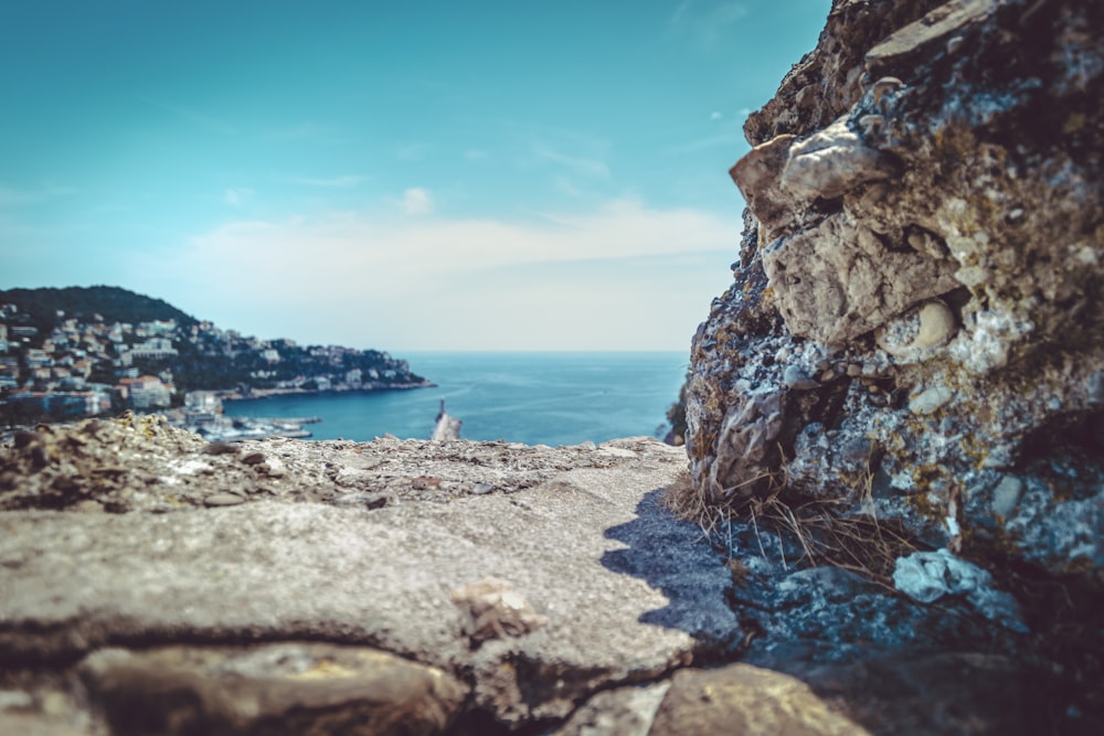 houses on cliff viewing blue sea under blue and white sky during daytime