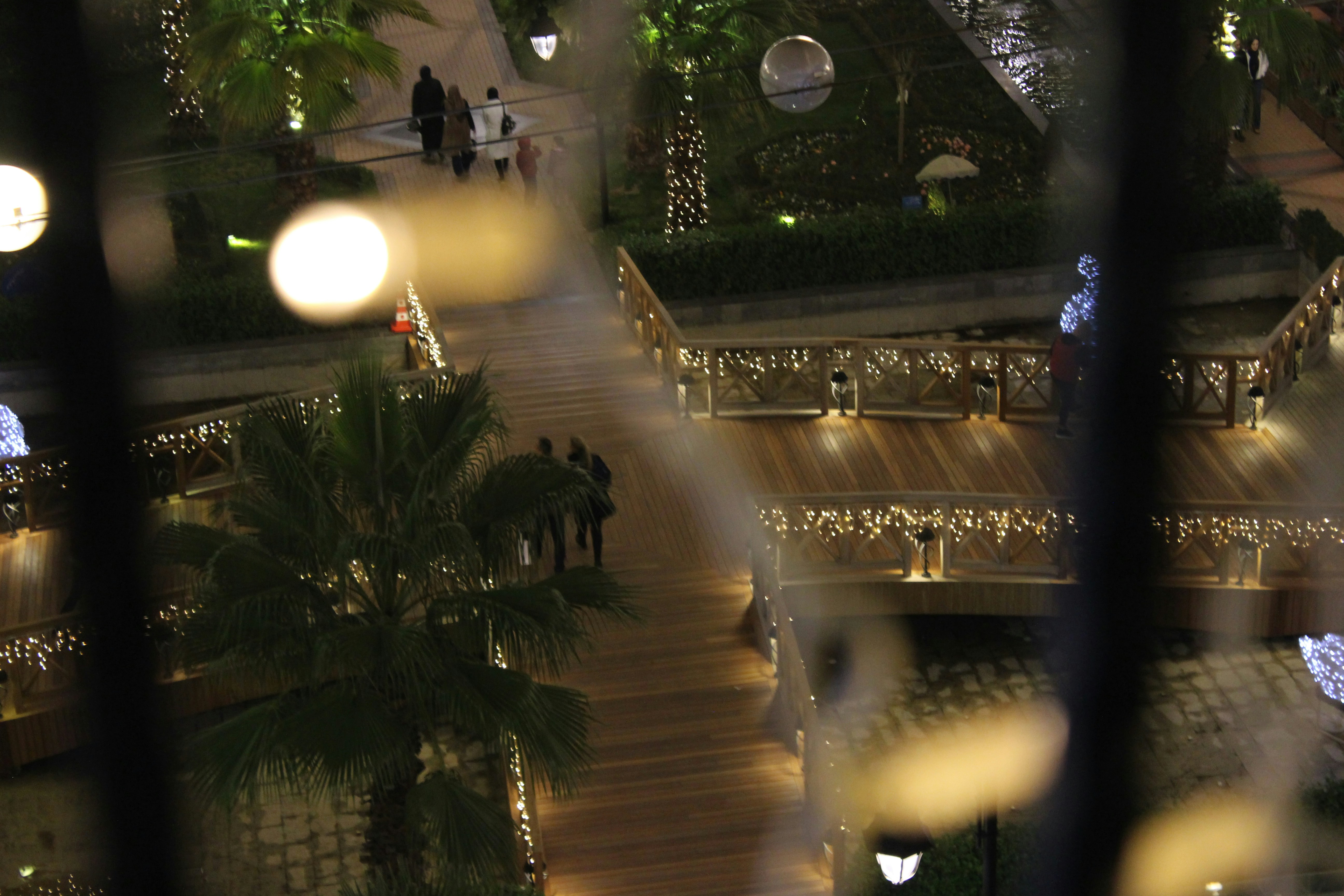 people walking on street through black metal window grill