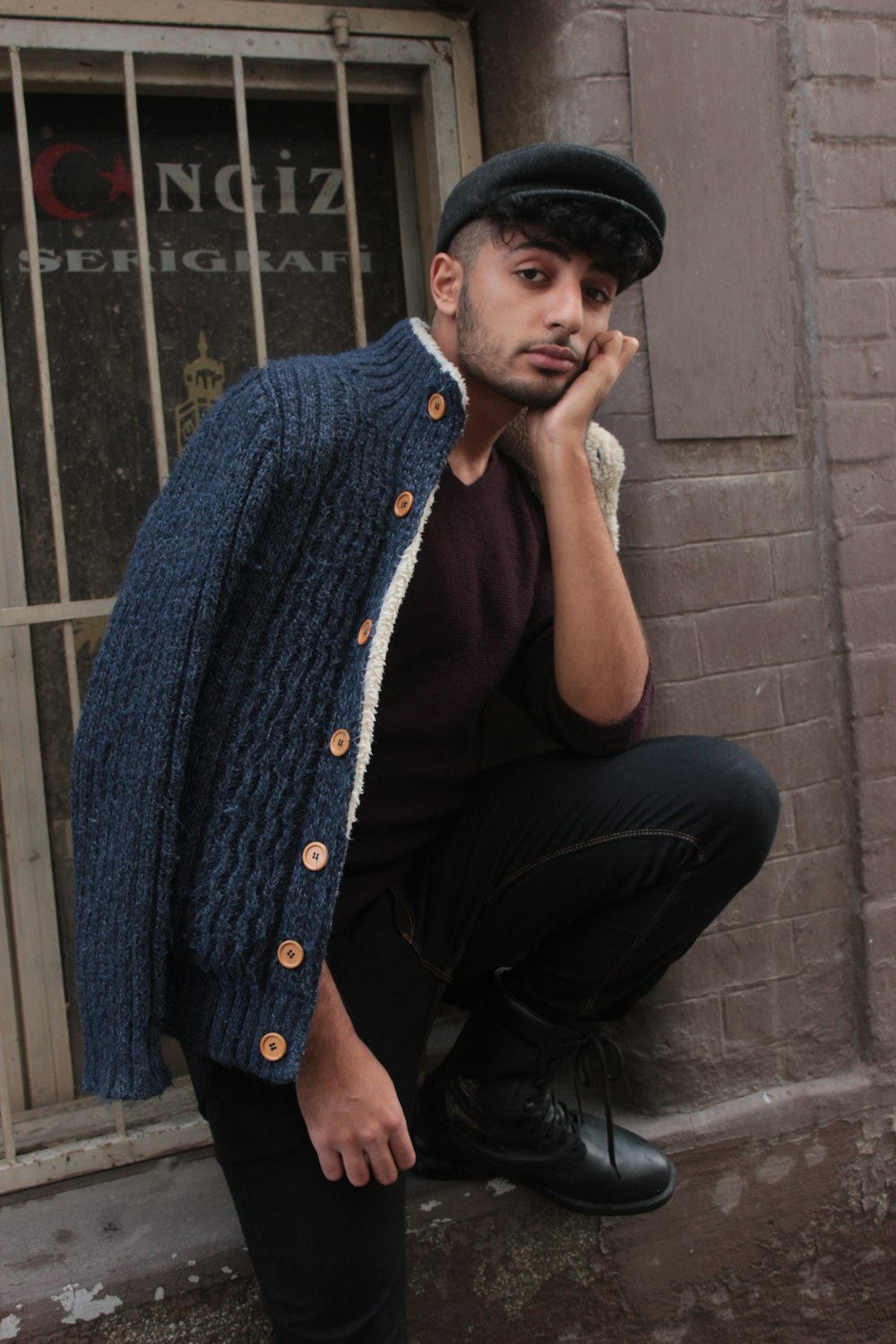 man leaning on wall with hand on chin