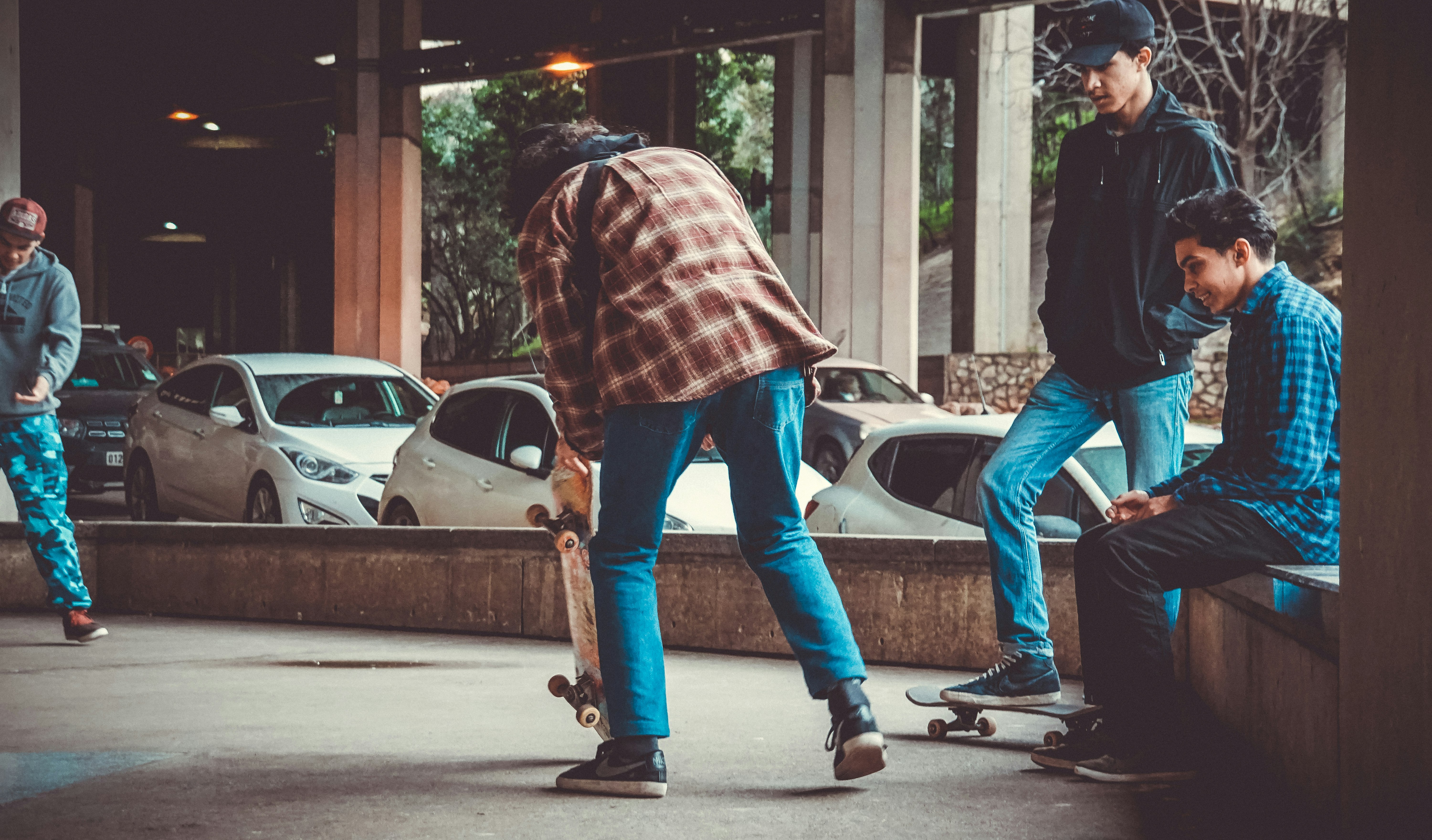 man holding skateboard while standing near another three men