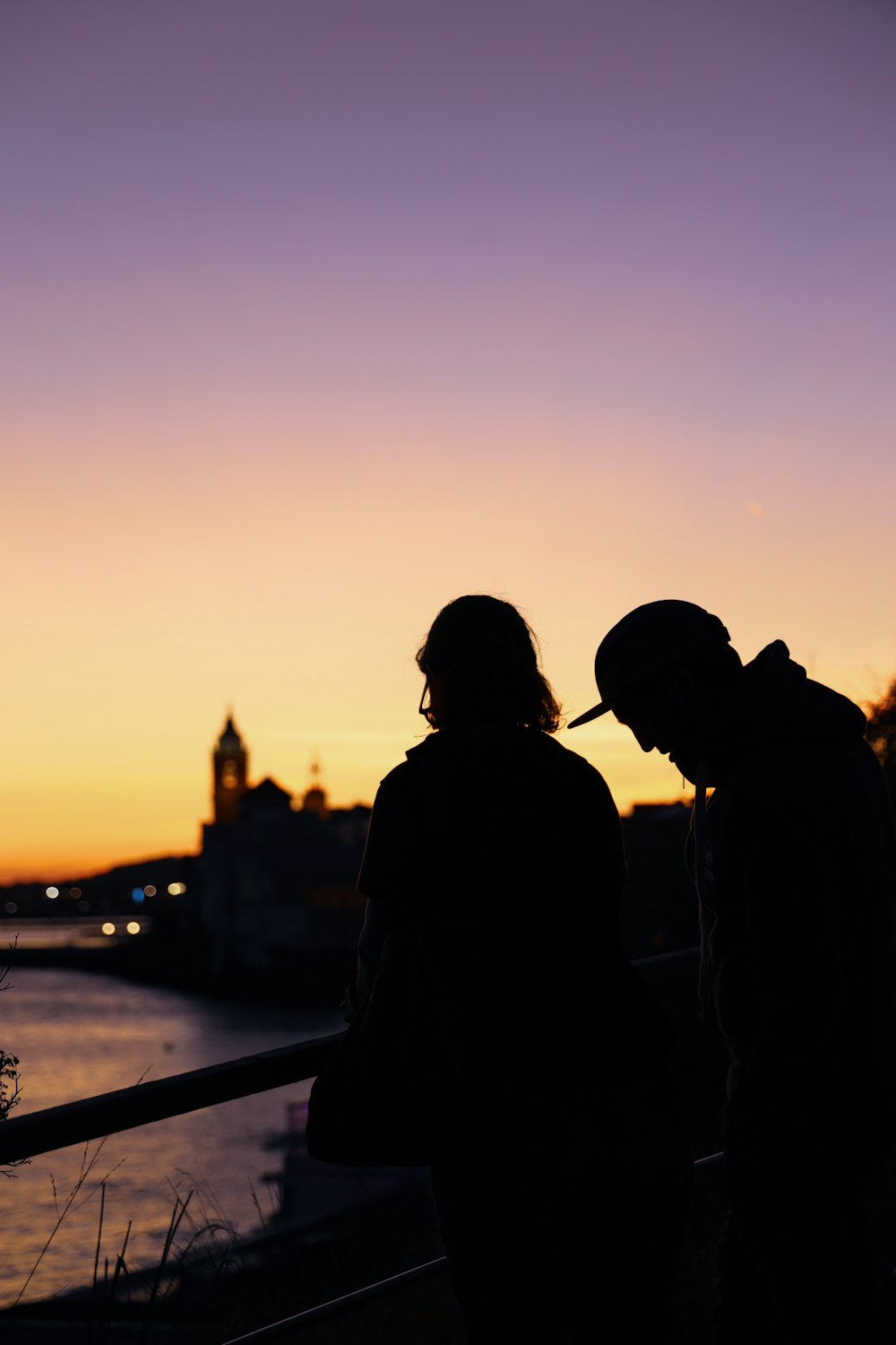 two people standing near railings viewing body of water