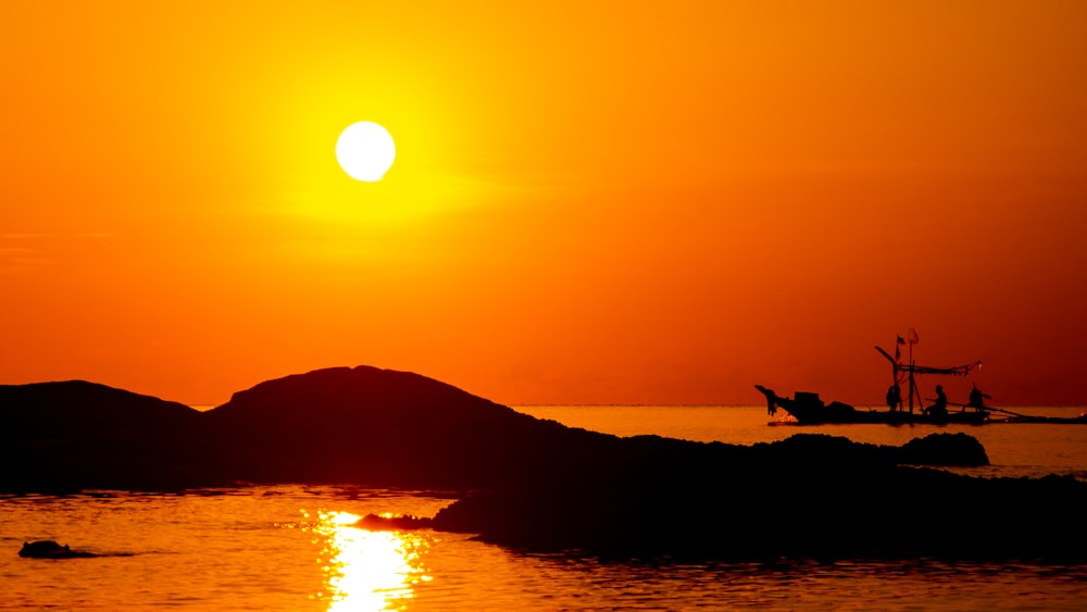 people in boat on body of water under orange sky