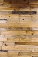 Numerous wooden planks arranged horizontally, showcasing a variety of natural patterns and textures. Some planks display darker stains and knots, adding character to the overall appearance.