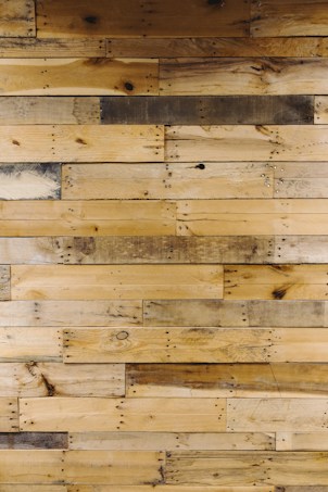 Numerous wooden planks arranged horizontally, showcasing a variety of natural patterns and textures. Some planks display darker stains and knots, adding character to the overall appearance.