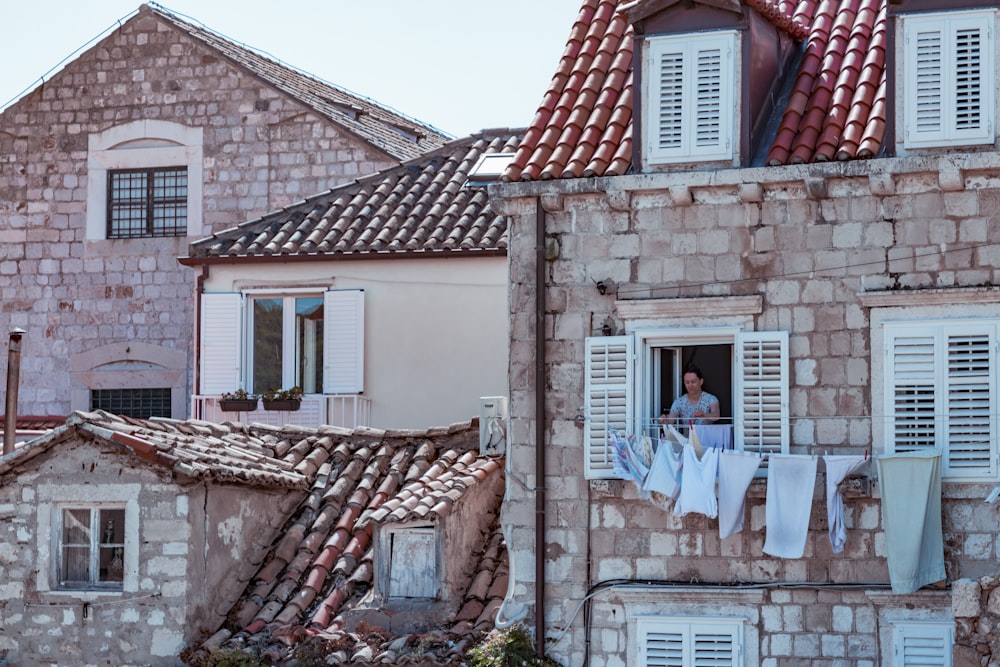 Frau steht vor Fensterhaus