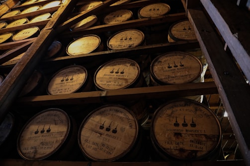 Close-up of a hand selecting a Kentucky bourbon barrel in a dimly lit rickhouse.