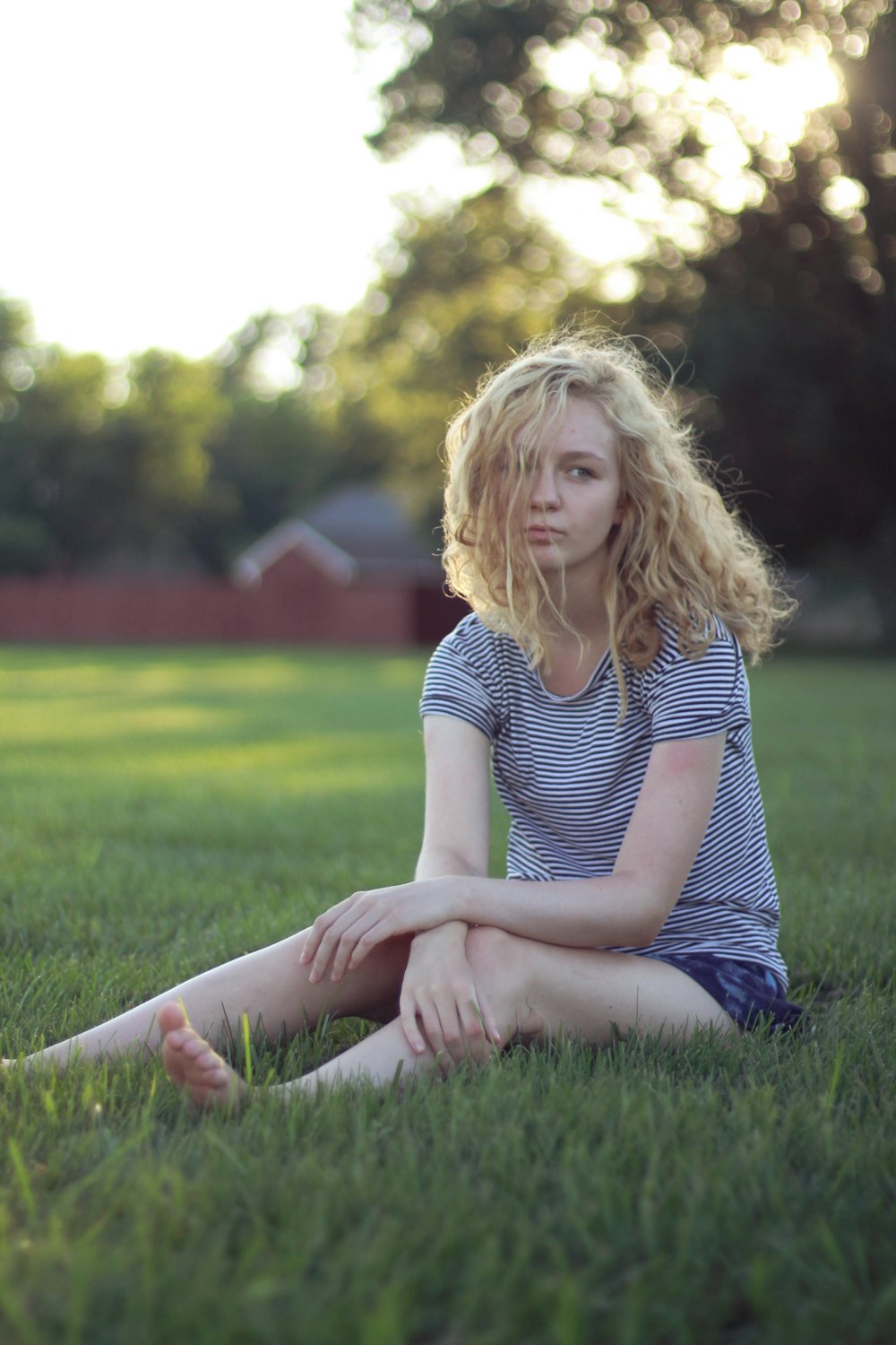 woman wearing blue and white striped crew-neck shirt sitting on grass field