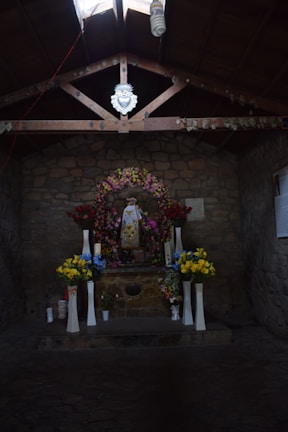Inside the chapel during a religious ceremony, showing the altar decorated with flowers and community members in prayer.