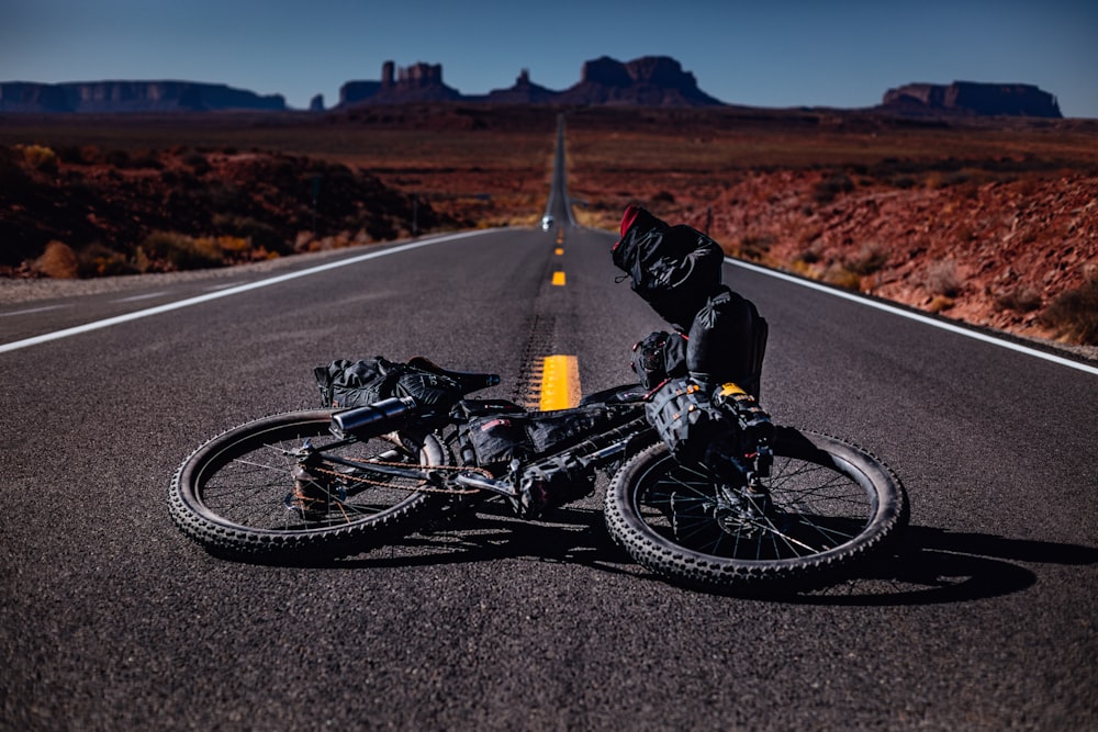 man sitting beside motorcycle on road