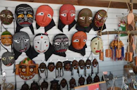 Colorful African masks hanging against an earthy textured wall, symbolizing cultural heritage.