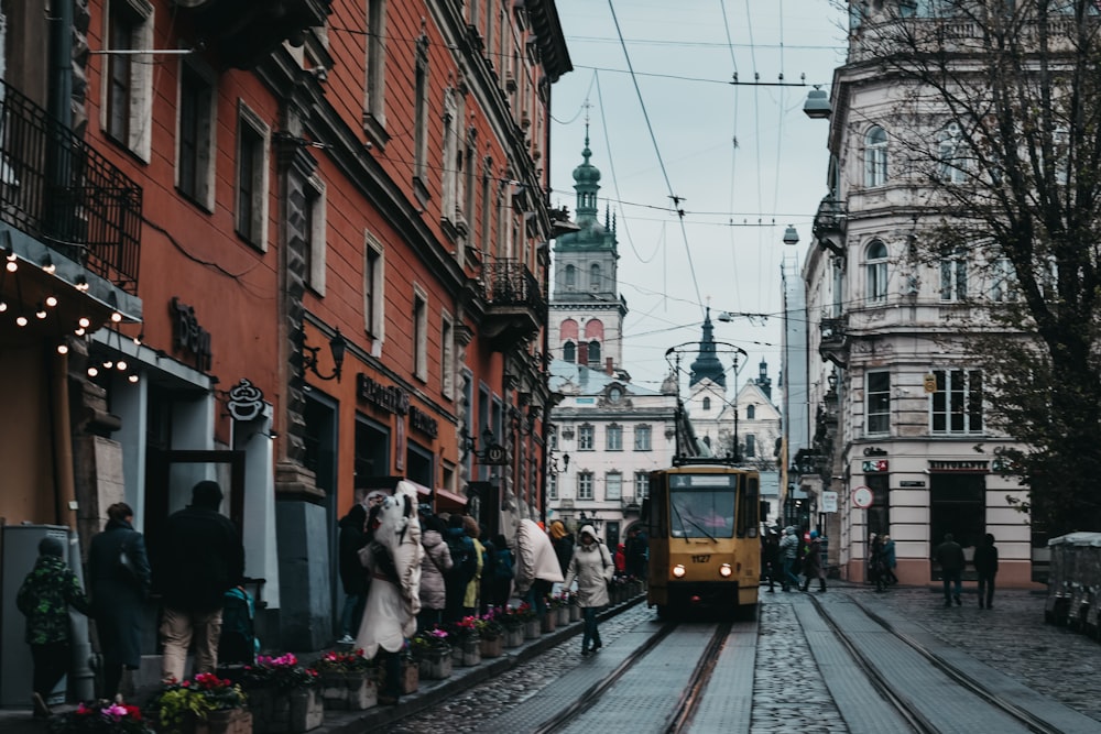 orange train on railroad beside people and buildings