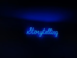 A neon sign with the word 'Storytelling' illuminated in bright blue against a dark background.