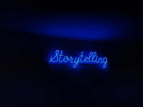 A neon sign with the word 'Storytelling' illuminated in bright blue against a dark background.