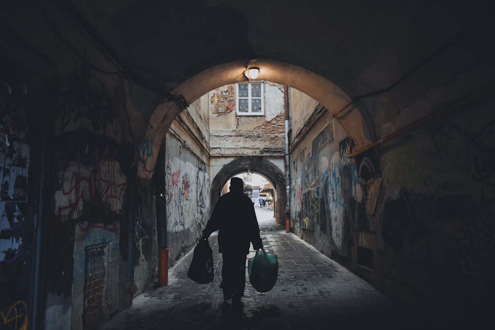 person holding plastic packs while walking on pathway