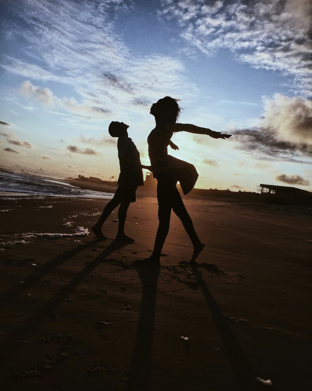 man and woman dancing near seashore nder white and blue sky