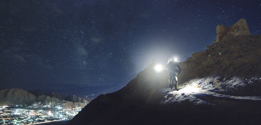 man holding turned-on flashlight standing on the cliff