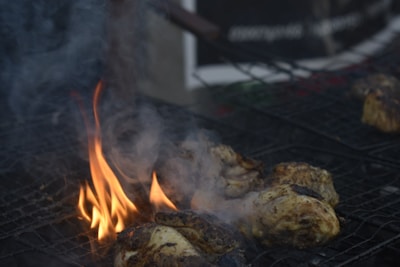 Grilled meats sizzling on a barbecue grill with smoke rising.