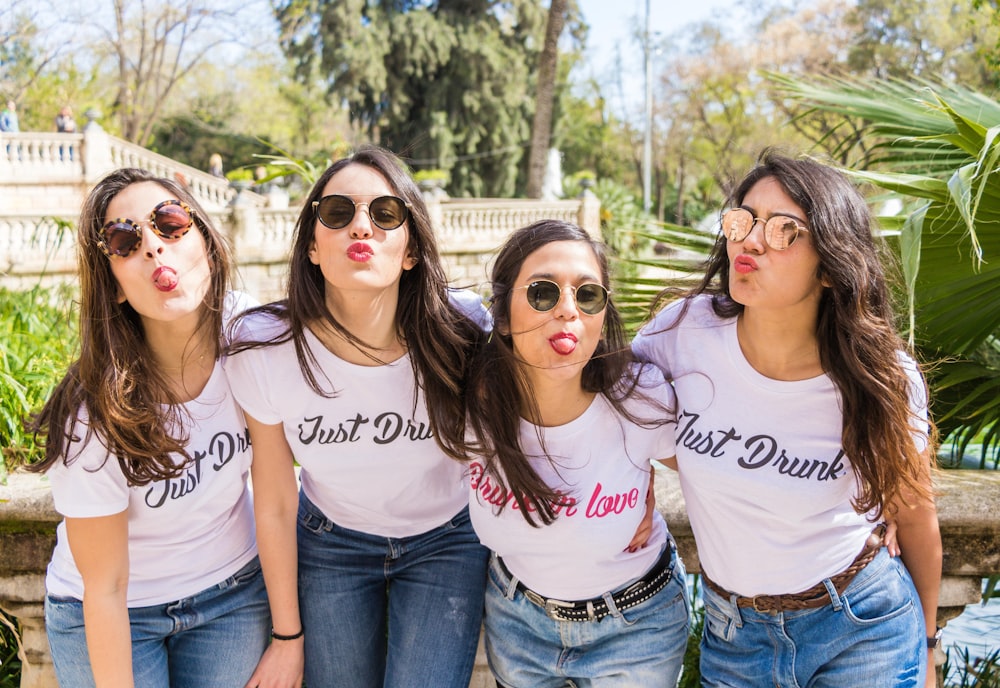 four women wears light pink crew-neck shirts