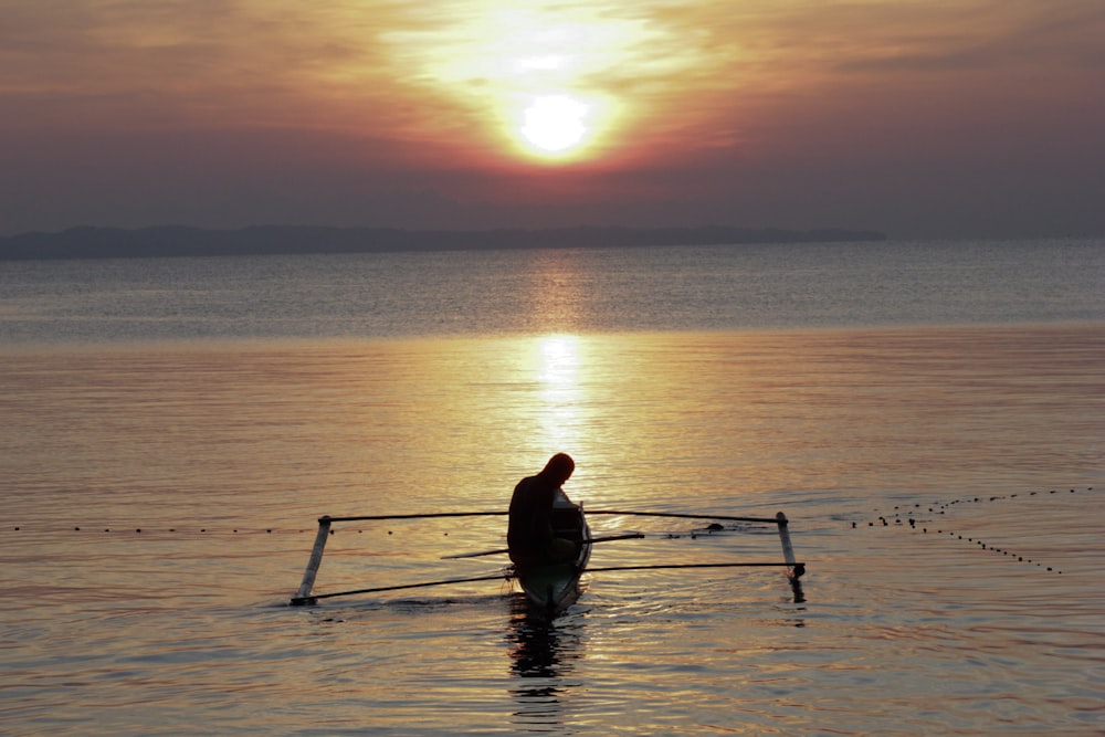 silhouette dell'uomo che cavalca la barca sullo specchio d'acqua calmo