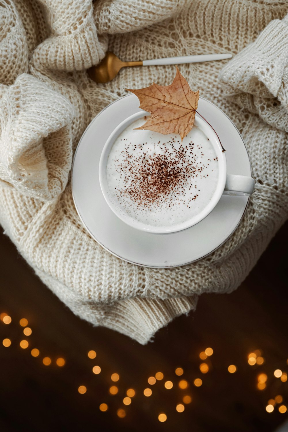 round white ceramic mug on white saucer on sweater