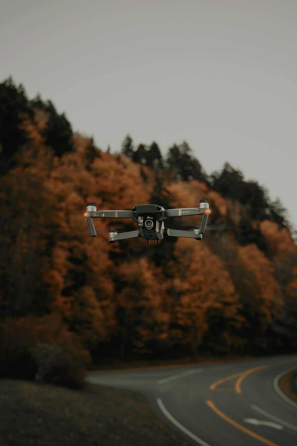 Mise au point sélective de la photographie d’un drone noir près d’une route sinueuse