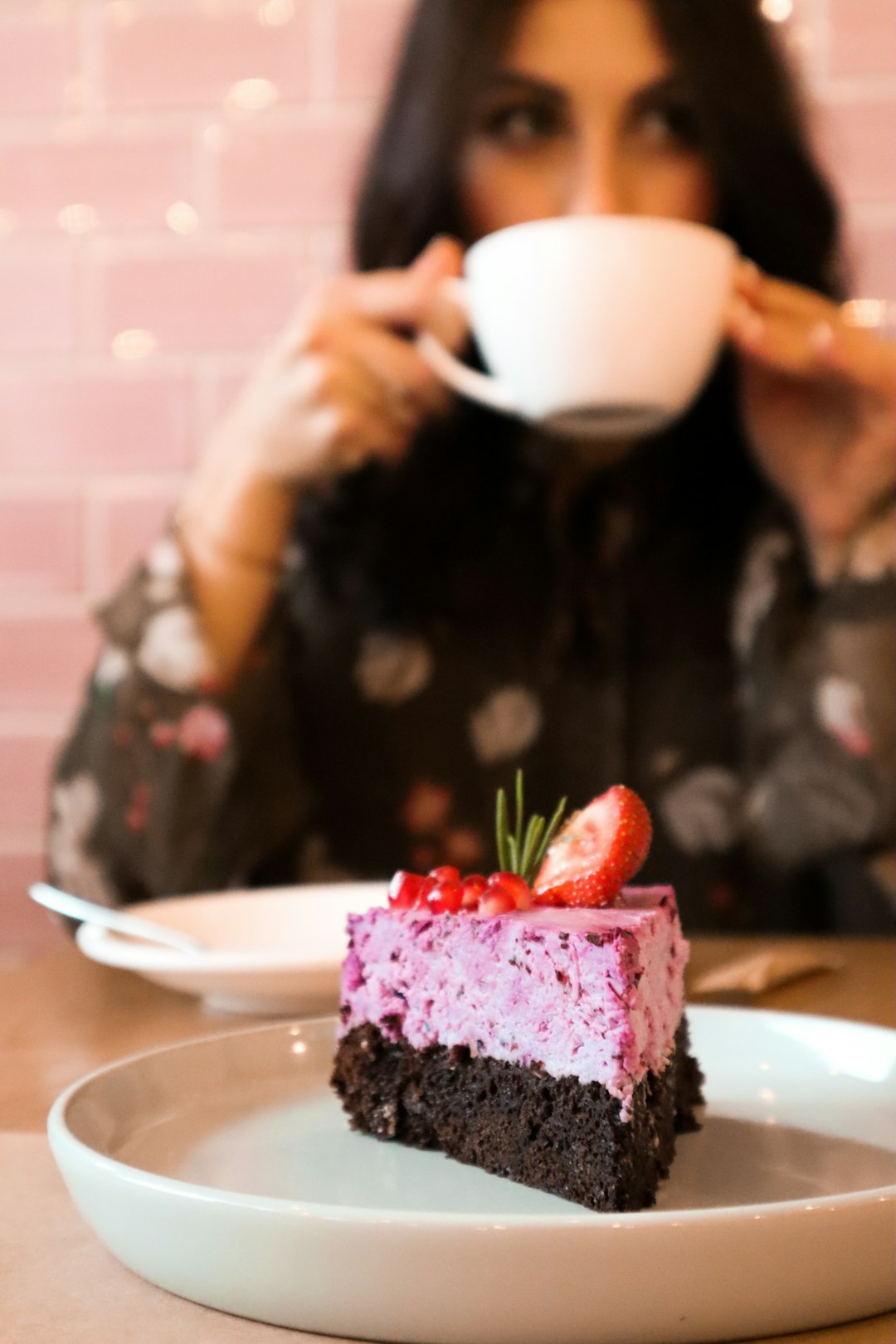 woman wearing black and white floral blouse holding white ceramic mug