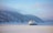 A large cruise ship navigates through icy waters surrounded by snow-covered mountains and a misty sky. The vast, tranquil scene captures the serene beauty of a winter landscape.