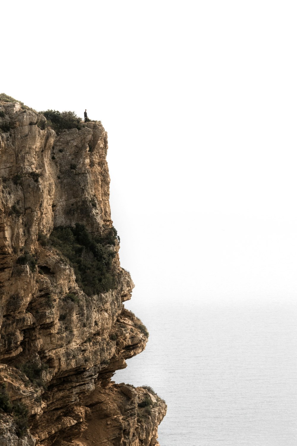 person standing on rock formation near body of water during daytime