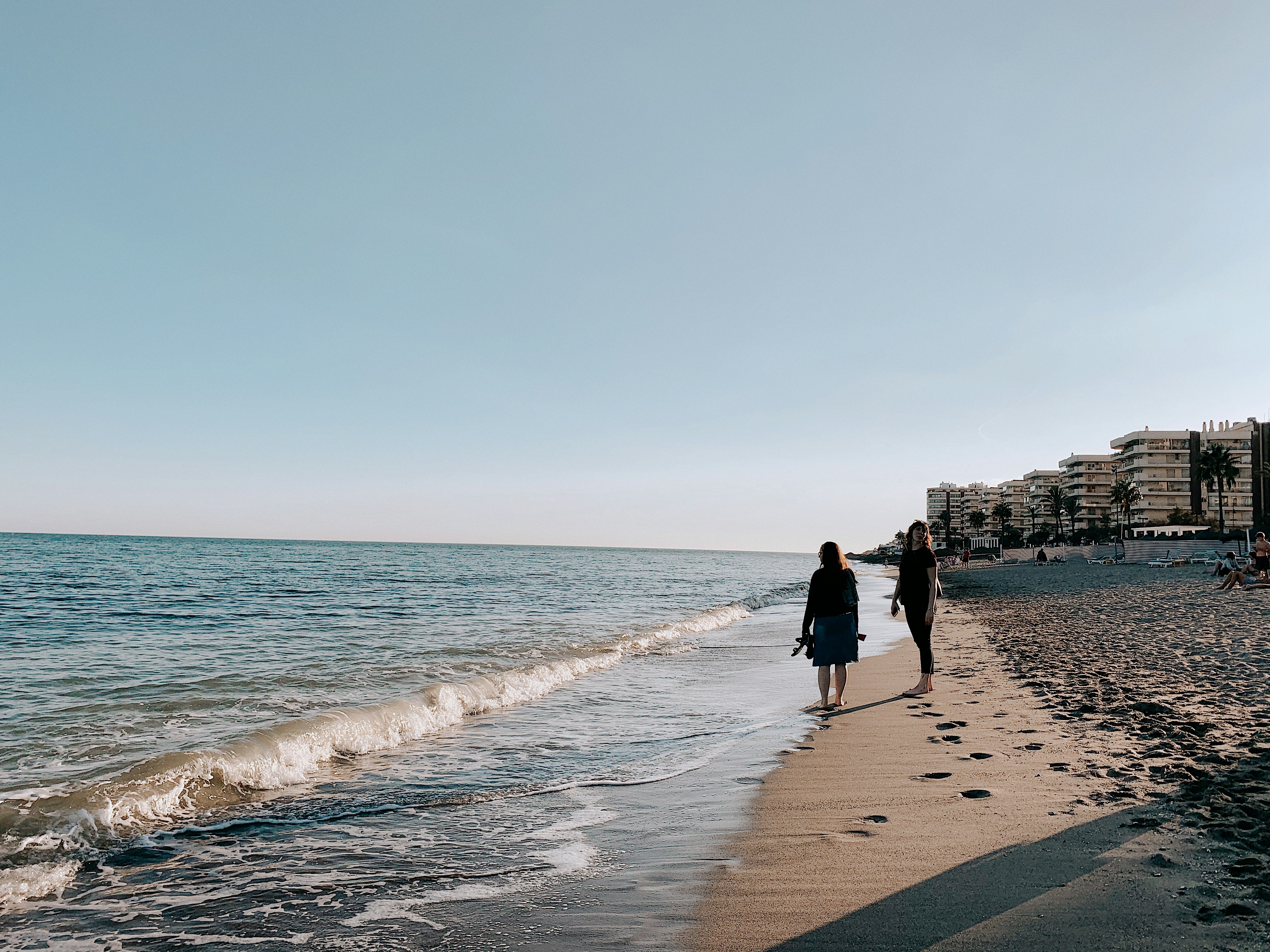 woman wearing black blouse walking on seashore