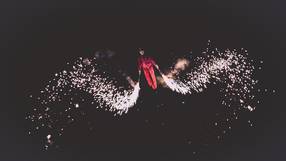 Person mit roter Jacke und Hose spielt Feuerwerk
