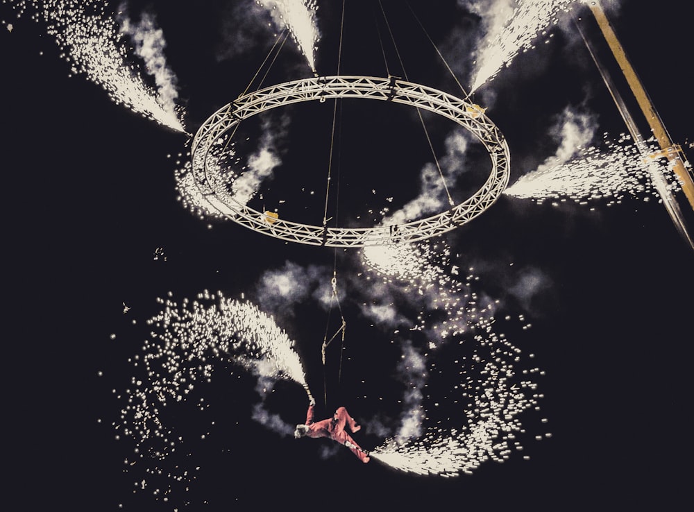 man holding sparkler hanging below ring with sparklers