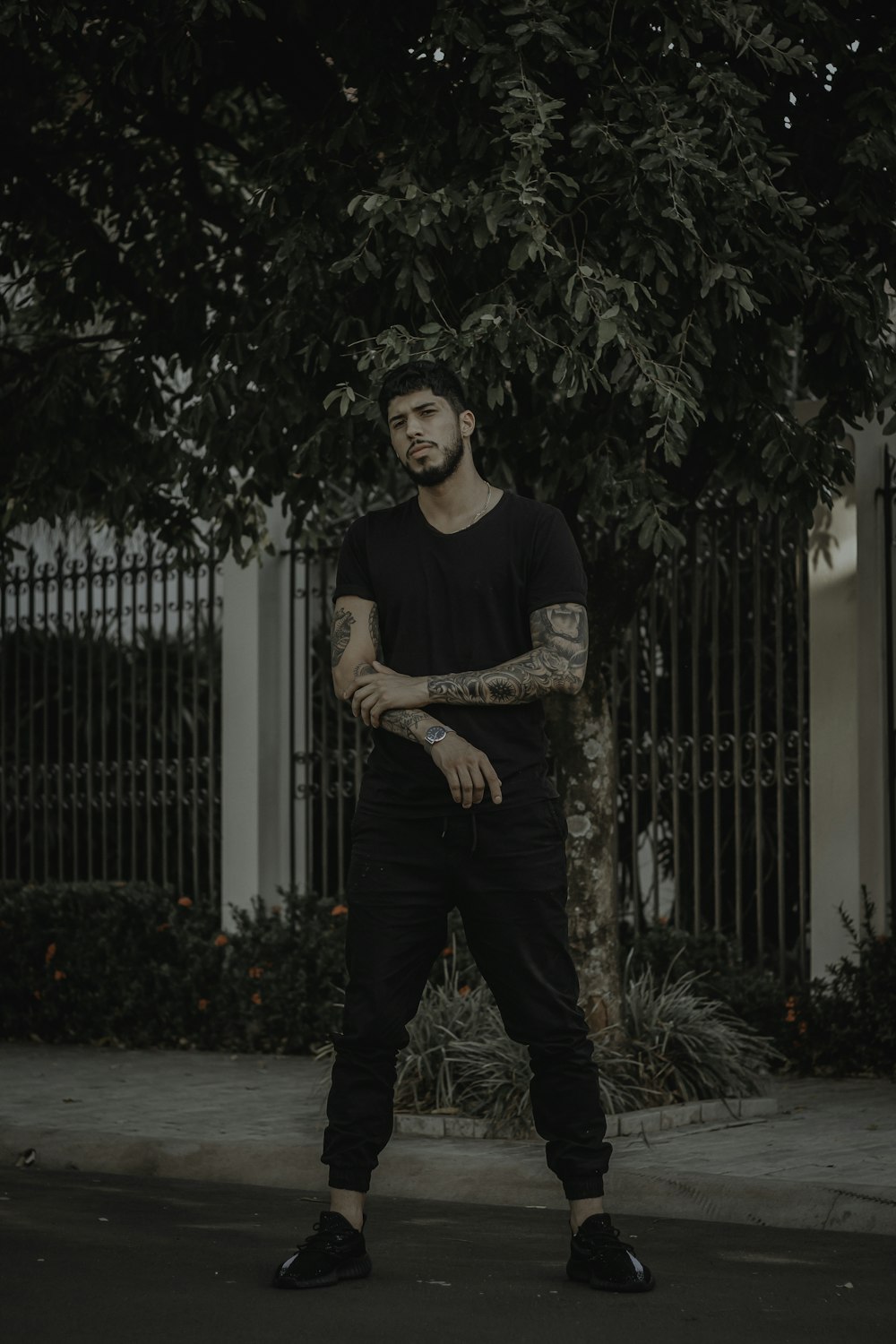 man in black shirt standing on road near fence