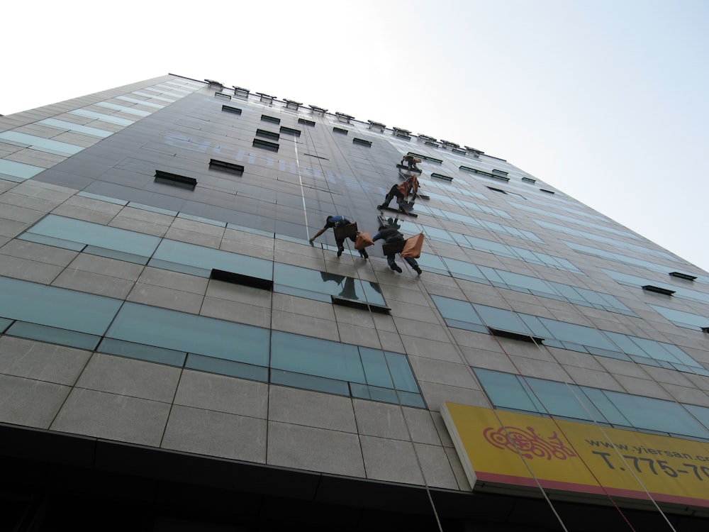 people climbing building under white sky