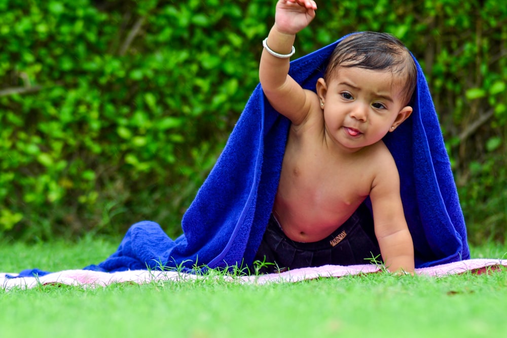 boy lying on blanket covered by blue towel