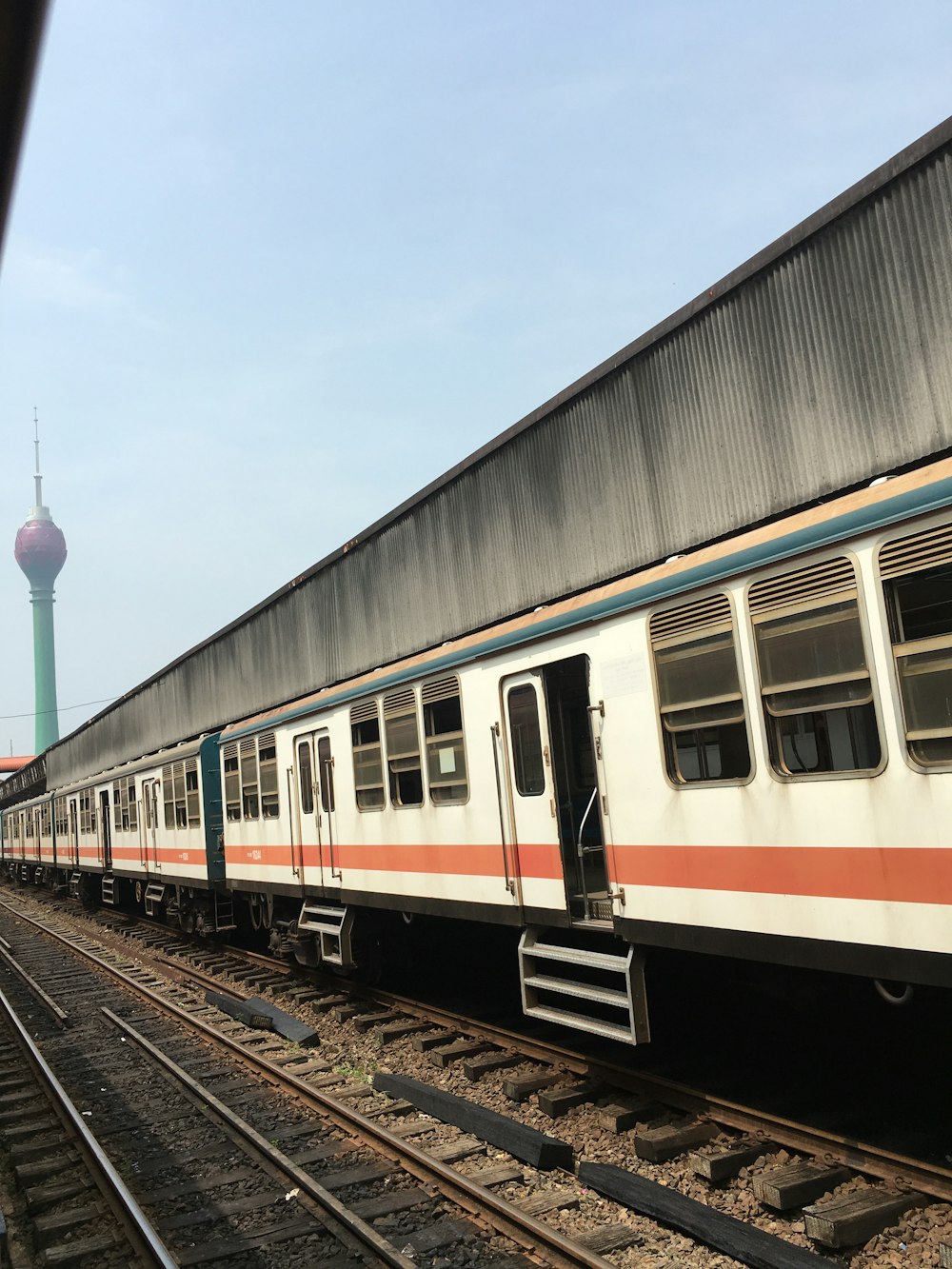 white, orange, and green train under blue and white sky during daytime