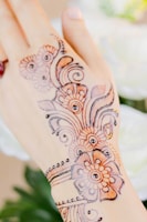 Close-up of vibrant henna designs on a bride's hands with soft focus wedding decorations.